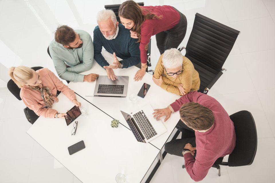Une équipe réunie autour d'une table de travail, vue de dessus, ordinateurs portables ouverts