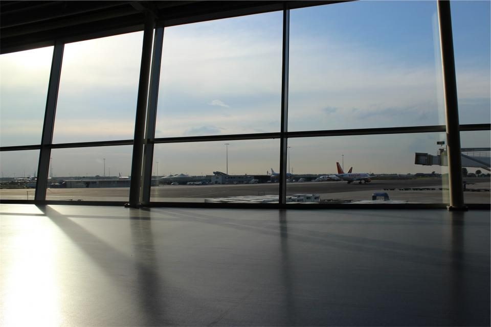 Un terminal d'aéroport : derrière la baie vitrée, un avion roule sur le tarmac